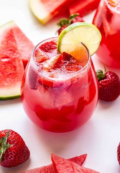 watermelon and limeade punch in a glass with sliced strawberries on the side