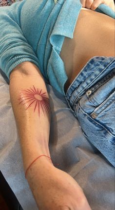 a woman laying on top of a bed with her arm tattooed to the side