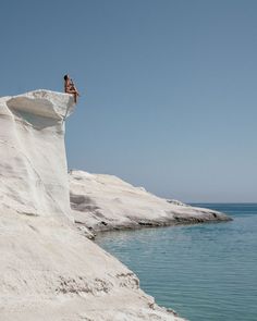 a person jumping off the side of a cliff into water