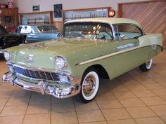 an old green car is parked in a showroom