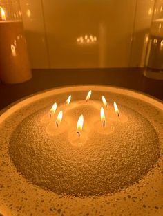 five lit candles sitting on top of a round table in the middle of a room