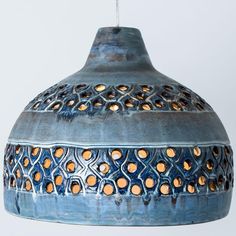 a blue hanging light with holes in the middle and an orange dot pattern on it