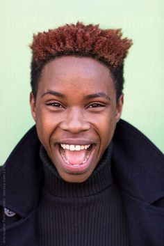 a young man with an afro is smiling and looking at the camera while wearing a black coat