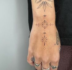 a person's hand with tattoos on it and an arrow tattoo on the wrist