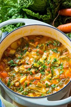 a pot filled with soup next to carrots and lettuce on a table