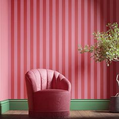 a pink chair sitting next to a potted plant on top of a wooden floor