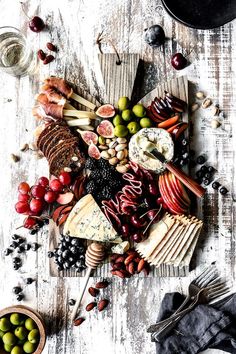 an assortment of cheeses, fruits and nuts on a wooden table