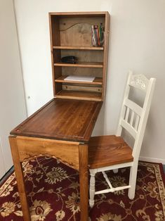 a wooden desk and chair sitting on top of a red carpeted floor in front of a white wall