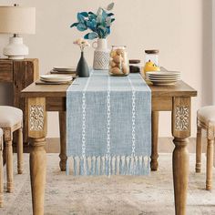 a dining room table set with plates, cups and vases on top of it