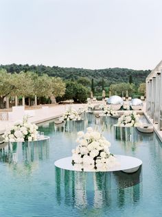 an outdoor wedding setup with white flowers and greenery on the water's edge