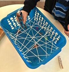 a child is playing with a basket made out of toothpicks and sticks on the table