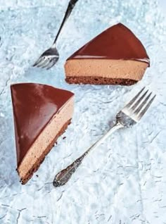 two slices of chocolate cheesecake on ice with forks