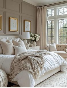 a large white bed sitting in a bedroom next to a window filled with lots of windows