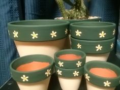 four pots with flowers painted on them are sitting next to a cactus plant in a pot