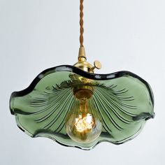 a green glass light hanging from a ceiling fixture with a cord attached to the end