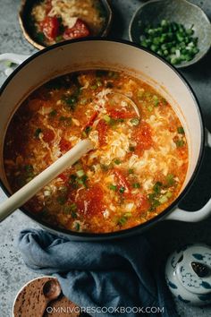 a large pot filled with soup on top of a table next to other bowls and spoons