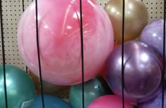 many different colored balloons in a cage