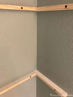 the corner of a room with two wooden shelves on one side and an unfinished shelf on the other