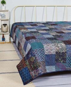 a bed with a blue and brown quilt on it's headboard next to a white bookcase