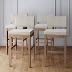 four white chairs sitting on top of a hard wood floor