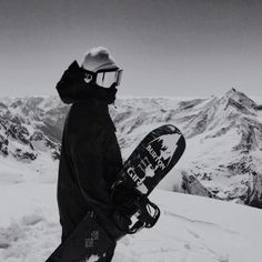 a snowboarder is standing on the top of a mountain with his board in hand