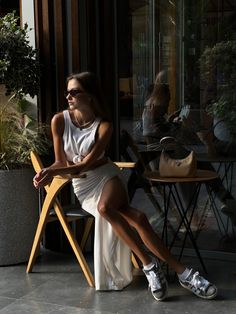 a woman sitting on a chair in front of a table with potted plants next to her