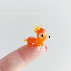 a tiny toy animal sitting on top of a finger