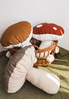 two stuffed mushrooms sitting on top of a bed next to a basket filled with pillows