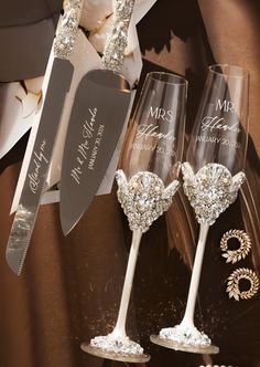 three wine glasses with personalized wedding gifts on them and a knife in the middle