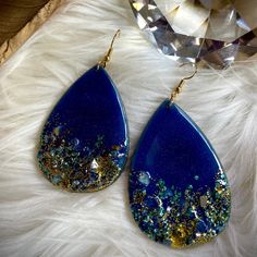 a pair of blue and gold earrings sitting on top of a white fur covered floor