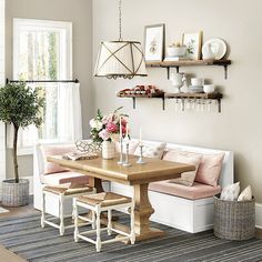 a dining room table with two benches and some flowers on the bench next to it