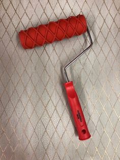 a paint roller laying on the floor next to a red handle