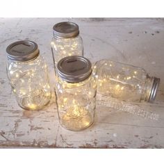 four mason jars with fairy lights in them