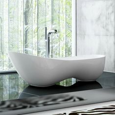 a bathroom with a large white bowl sink in front of a window that has trees outside