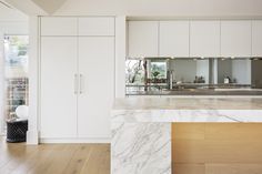 a kitchen with white cabinets and marble counter tops, along with an island in the middle