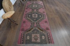 a long rug on the floor in a room with wooden floors and chairs around it