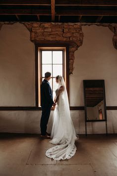 a bride and groom standing in front of a window