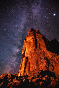 the night sky is filled with stars above a rocky outcropping and some rocks