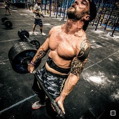 a man holding a barbell while standing on top of a gym floor