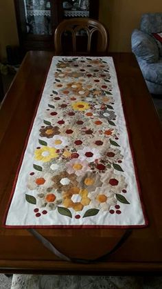 a table runner with flowers on it sitting on top of a wooden dining room table