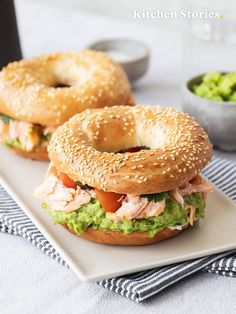 two bagels with salmon and guacamole on them sitting on a plate