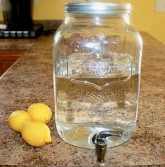 two lemons are sitting on the counter next to a mason jar that is filled with water