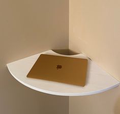 an apple laptop sitting on top of a white shelf next to a brown mouse pad