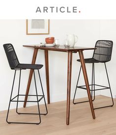 two chairs and a table in front of a white wall with the words article on it