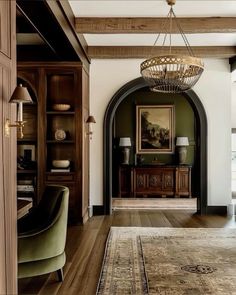 a living room filled with furniture and a chandelier hanging over it's doorway