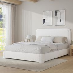 a white bed sitting in a bedroom on top of a hard wood floor next to a window