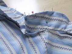 a blue and white striped shirt with small pins sticking out of the chest, sitting on a table