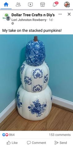 three stacked pumpkins sitting on top of each other in front of a blue wall