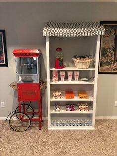 a red and white machine sitting on top of a book shelf next to a wall