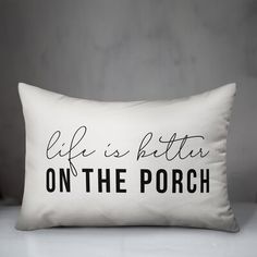 a white pillow that says life's little on the porch with black lettering in it